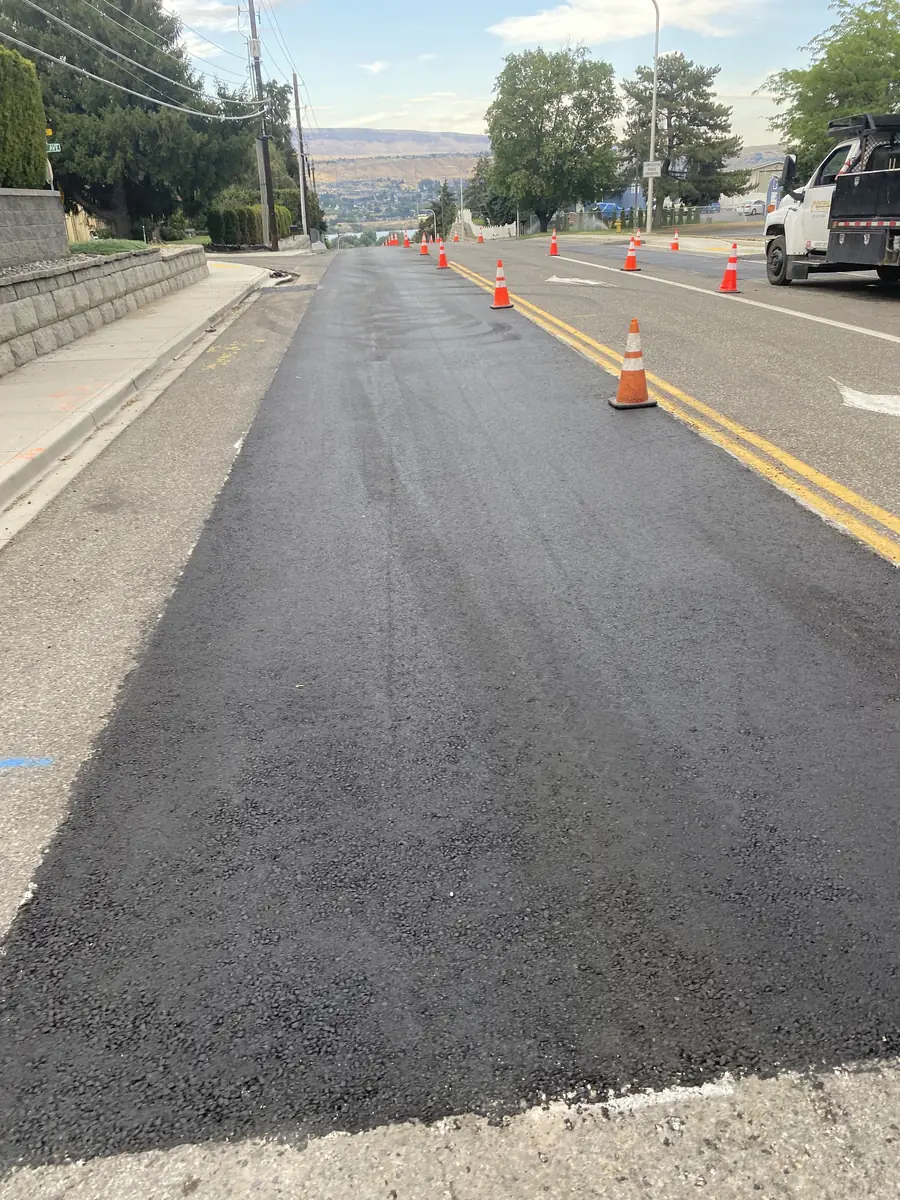 Fresh asphalt lane with orange traffic cones along the shoulder