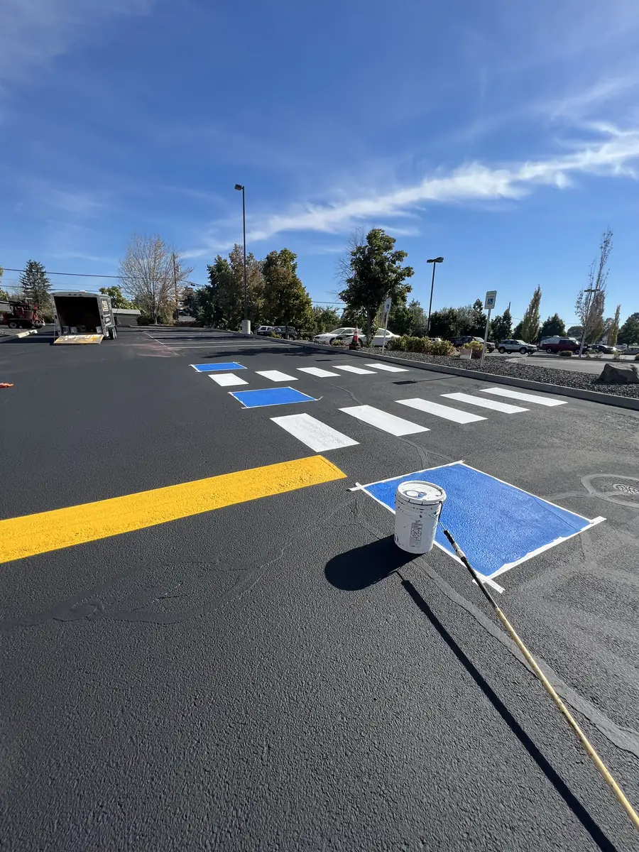 Newly striped crosswalk with a blue accessible symbol and yellow line