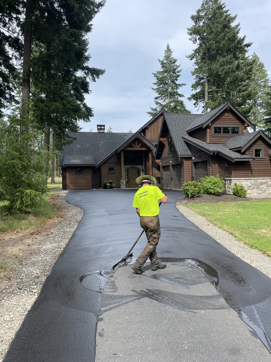 Crew member working on a paved driveway at a log-style home