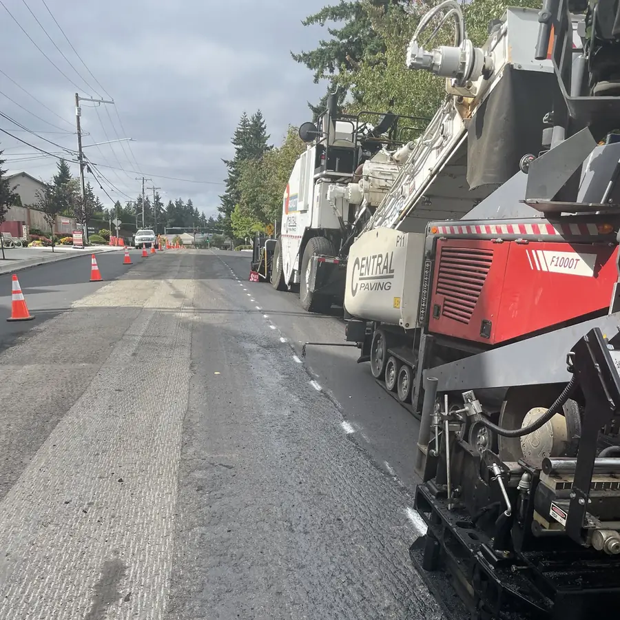 Large red and white paver and a paving crew on a neighborhood street