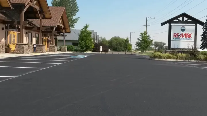 Freshly sealcoated commercial parking lot with new white stall lines in front of an office building