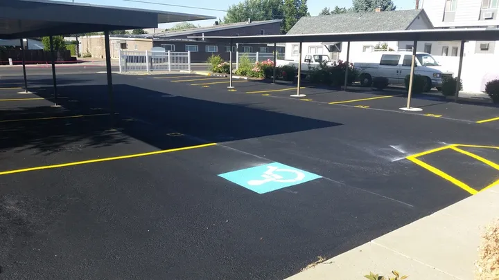 Sealcoated covered parking area with a blue accessible symbol and yellow striping