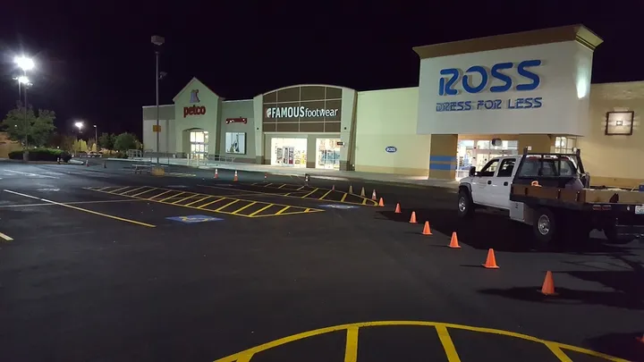 Sealcoated and restriped shopping center parking lot at night with traffic cones