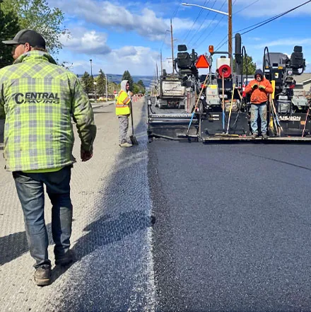 Paving crew working behind an asphalt paver on a city street